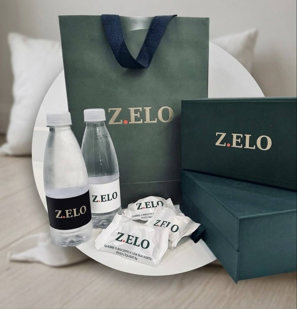 Kit do Protocolo Z.ELO: sacola e caixas verdes, água e biscoitos com a marca.