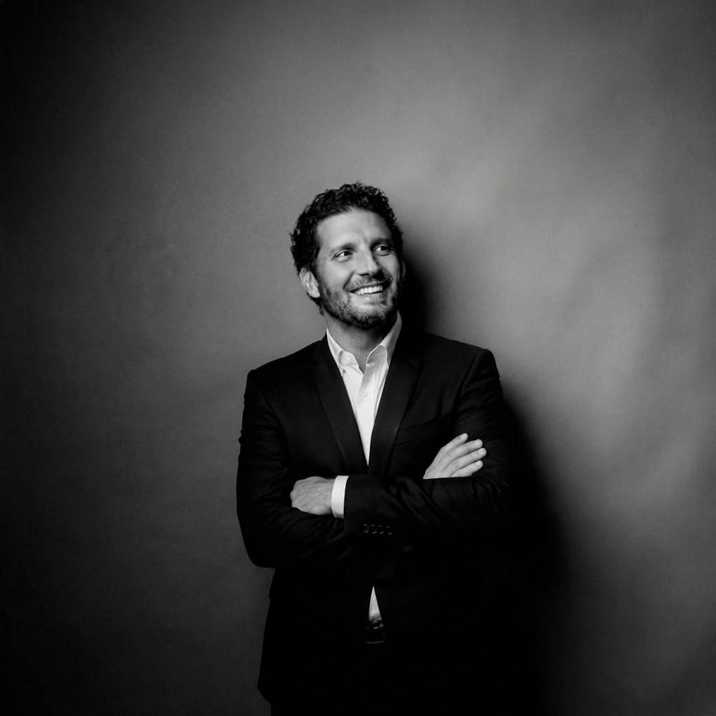 Dr. Bruno Saldini encostado em uma parede, sorrindo, retrato em preto e branco.