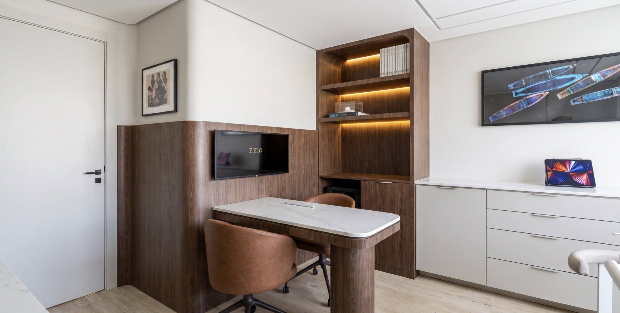 Sala de planejamento com mesa de madeira, cadeiras de couro e tela na parede.